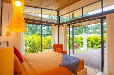 Habitación con aire acondicionado y ventanales al jardín tropical en Ceiba, villa ubicada en Playa Negra, Puerto Viejo.
